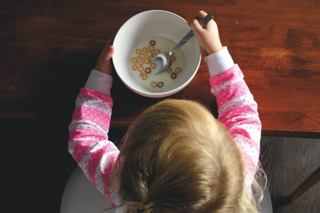 A child eating cereal and milk from a bowl.