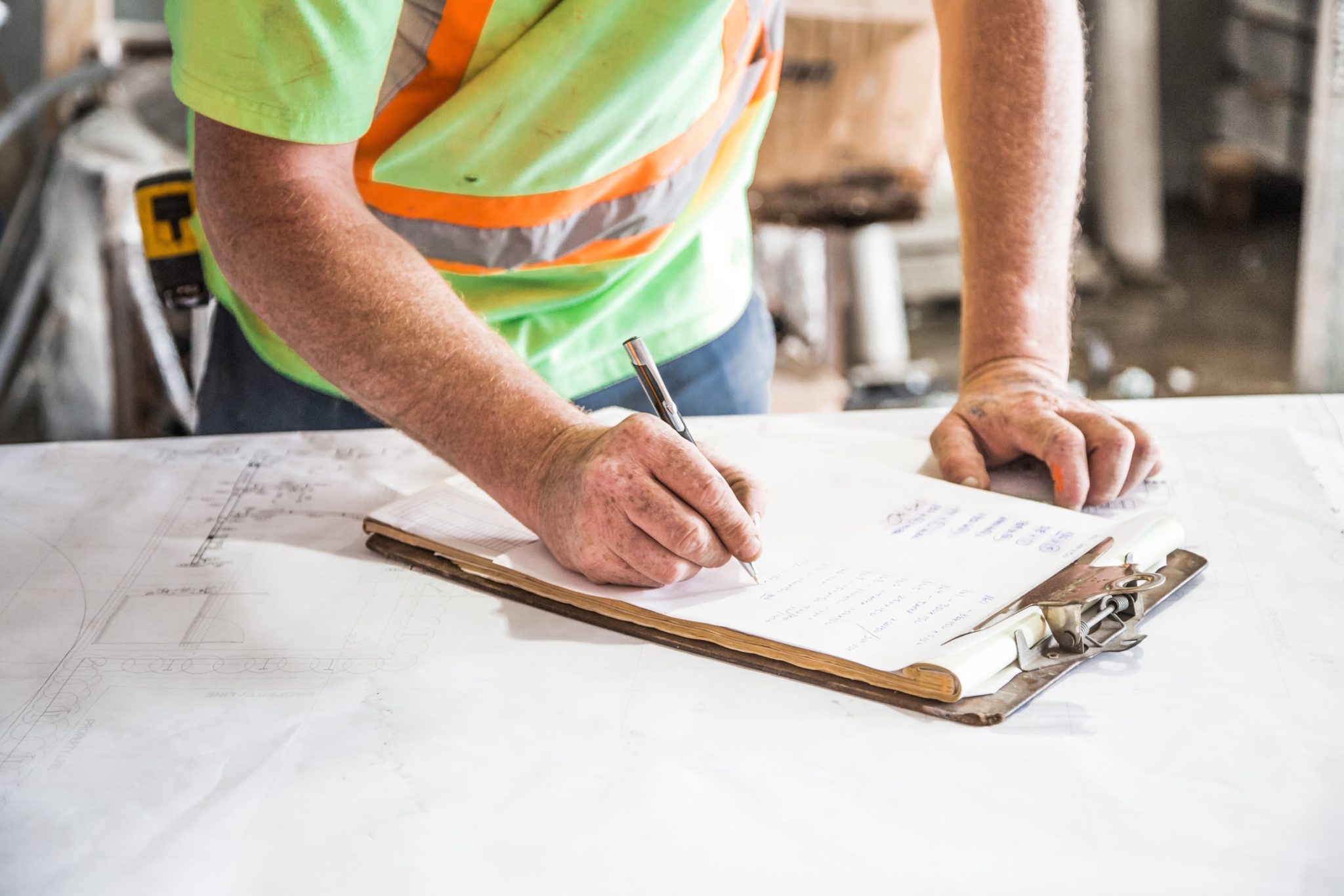 A construction worker writes on a clipboard.