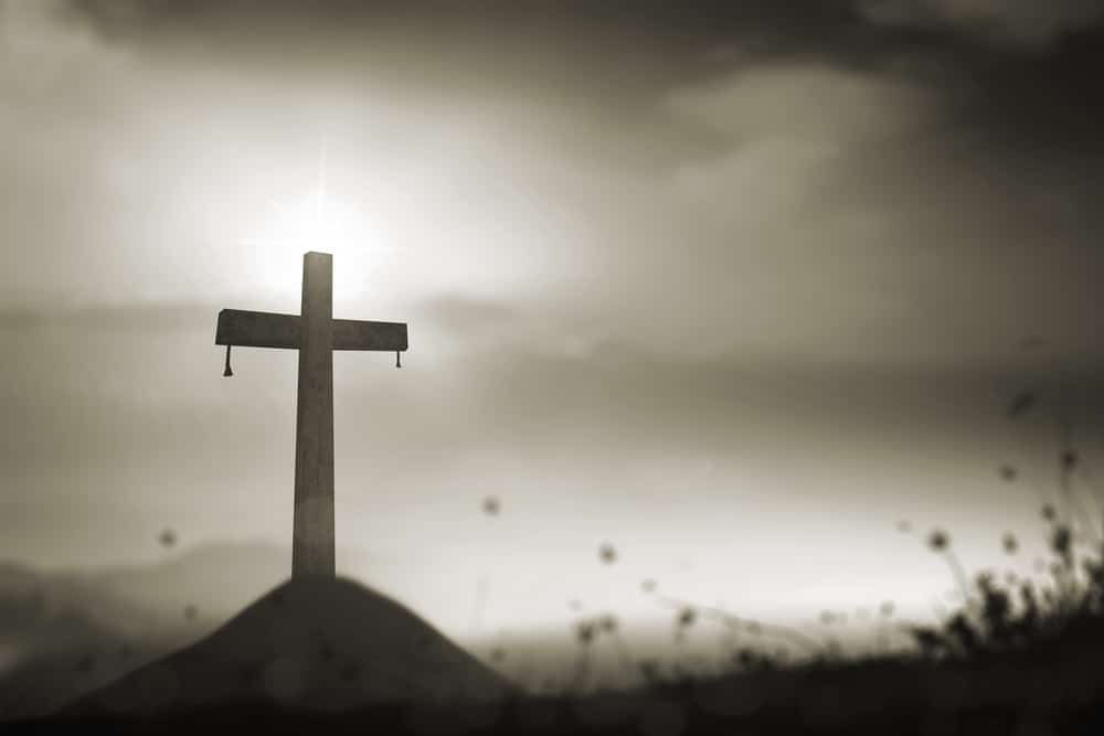 A lone cross on a hill. The image looks solemn.